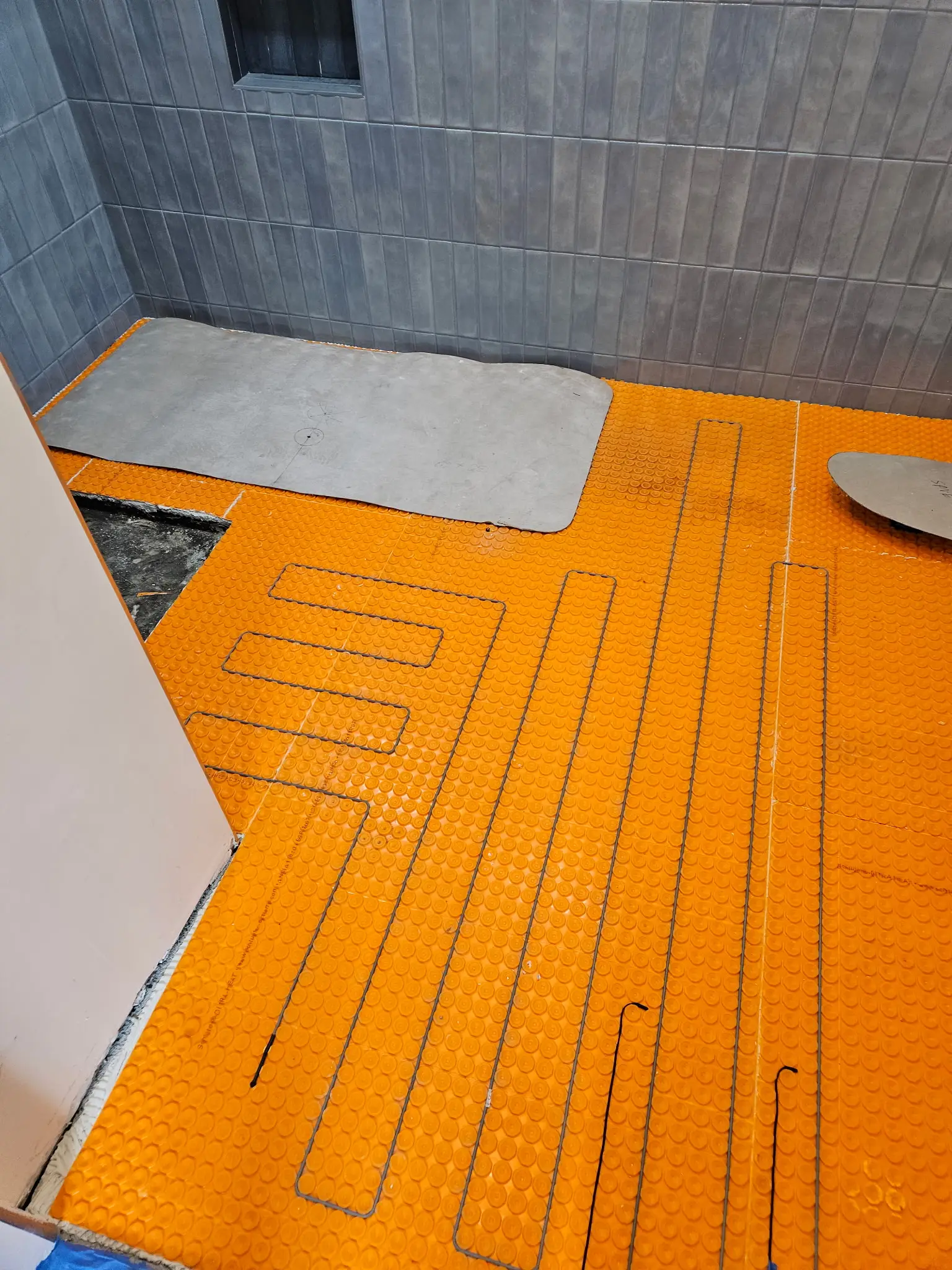 Electric radiant heating cable laid into orange uncoupling matting before tiling
